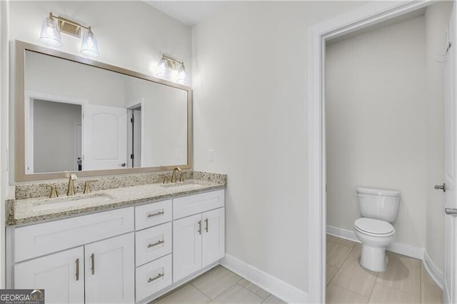 full bath with double vanity, a sink, toilet, and baseboards