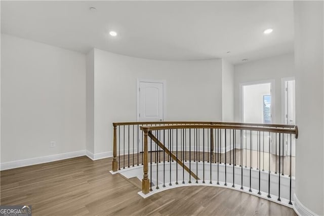 hall with recessed lighting, wood finished floors, an upstairs landing, and baseboards