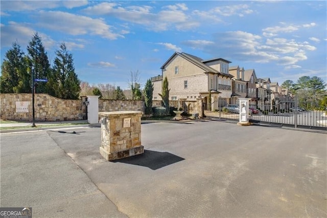 view of street with curbs, a gated entry, a gate, and a residential view