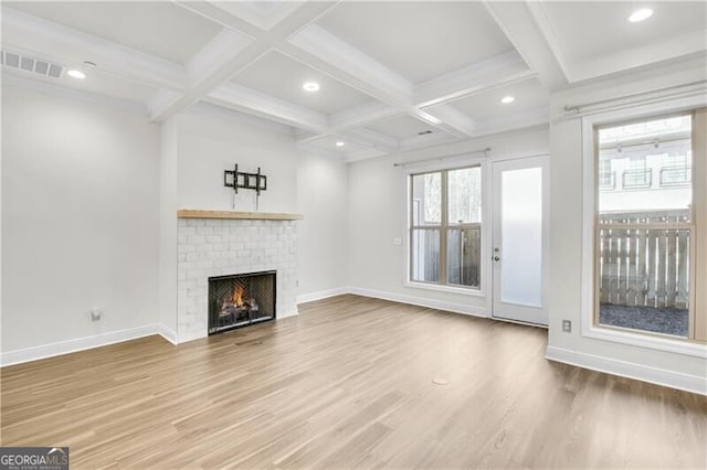 unfurnished living room with a brick fireplace, beam ceiling, coffered ceiling, and wood finished floors