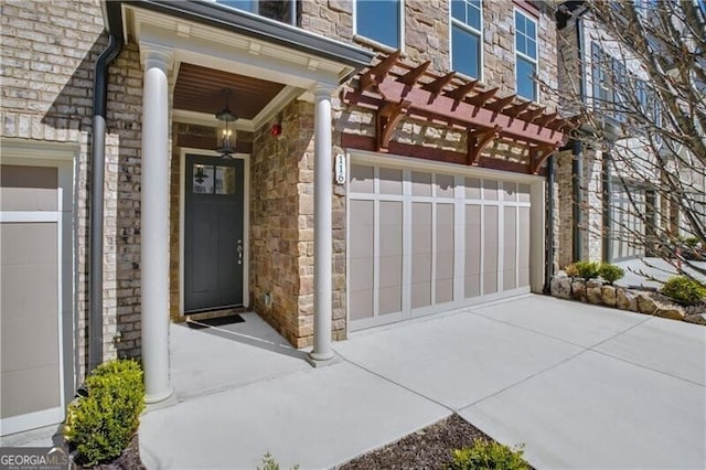 property entrance featuring a garage, stone siding, and concrete driveway