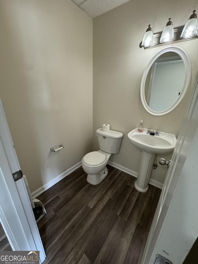 bathroom featuring toilet, a textured ceiling, baseboards, and wood finished floors