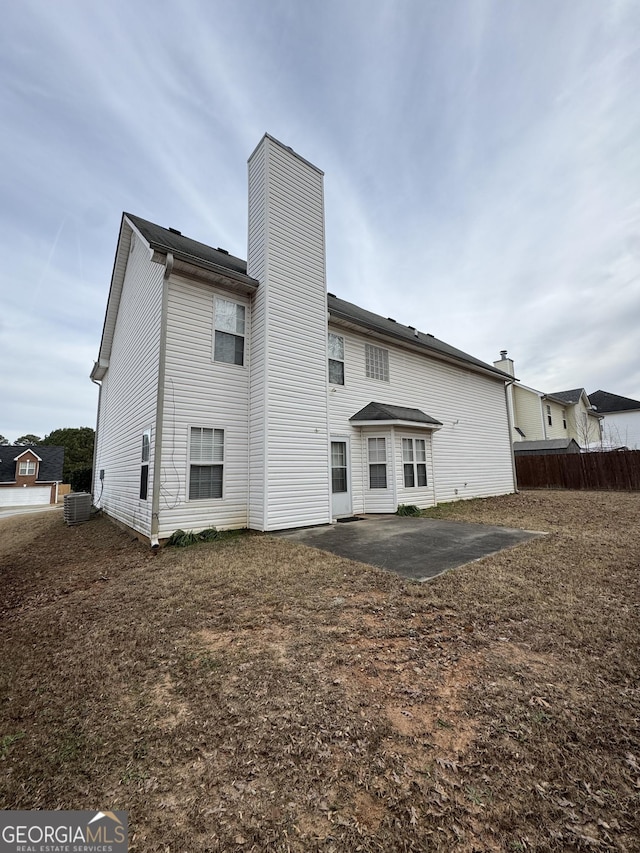 rear view of property featuring cooling unit, a patio area, fence, and a chimney