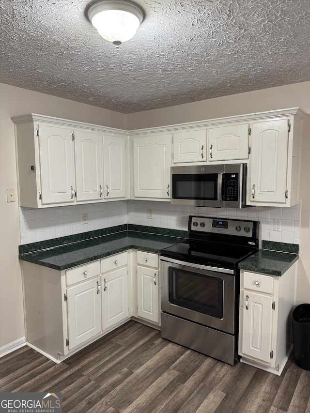 kitchen featuring dark countertops, dark wood-style floors, white cabinetry, and appliances with stainless steel finishes