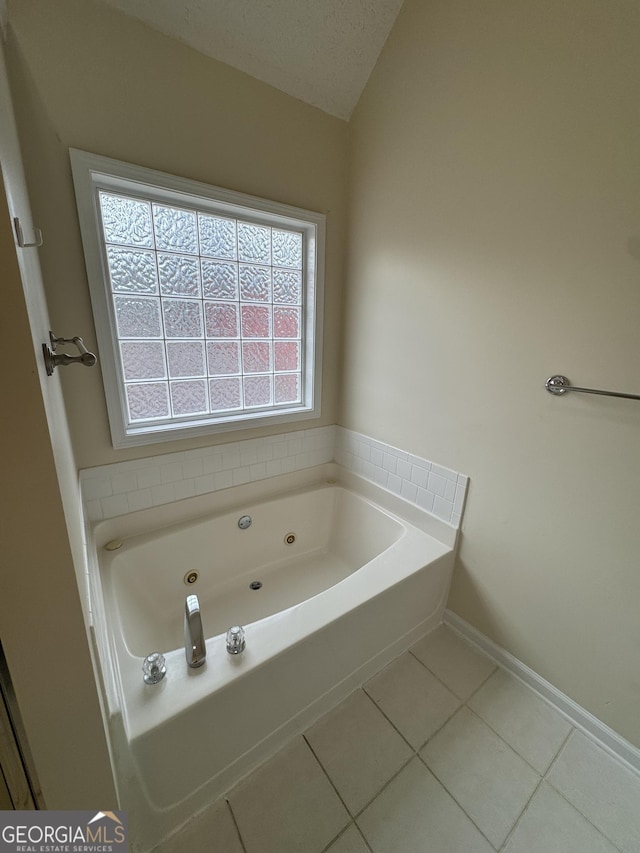 bathroom featuring lofted ceiling, baseboards, a tub with jets, and tile patterned floors