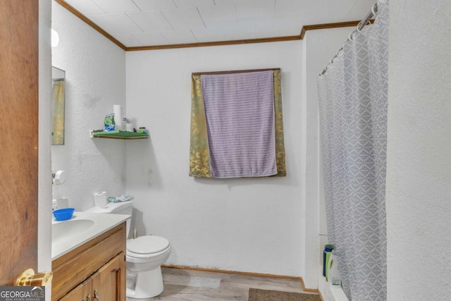 bathroom with a textured wall, toilet, ornamental molding, wood finished floors, and vanity