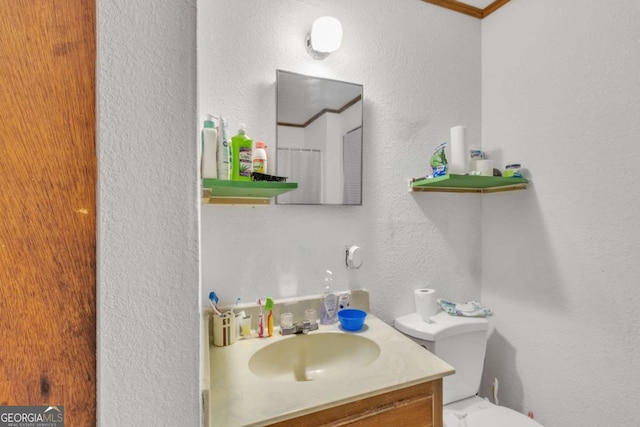 full bath featuring a textured wall, vanity, and toilet