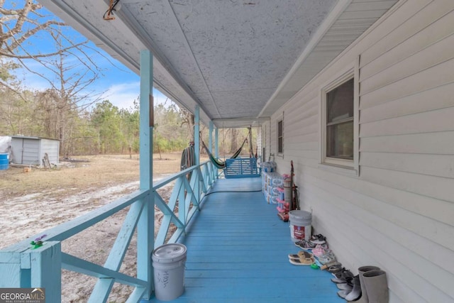 deck with a porch, an outdoor structure, and a shed