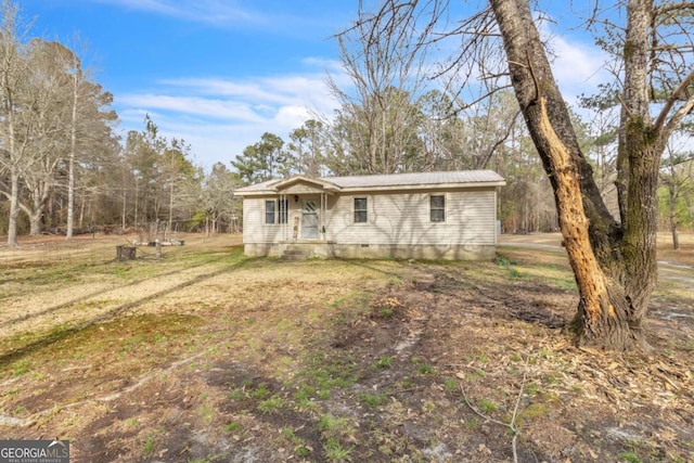 view of front of property featuring metal roof, a front lawn, and crawl space