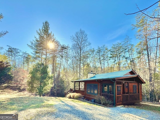 exterior space featuring a chimney, metal roof, and a porch