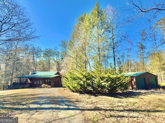 exterior space featuring driveway, a detached garage, a porch, and an outdoor structure