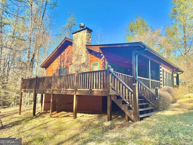 rear view of house with stairs, a yard, a chimney, and a wooden deck