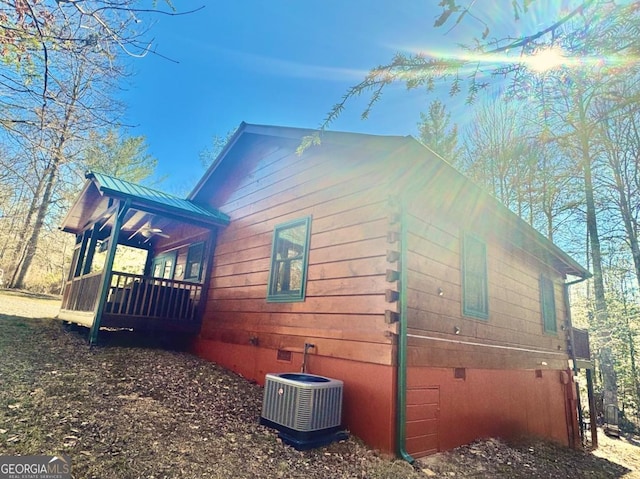 view of side of property with crawl space, a standing seam roof, central air condition unit, and metal roof