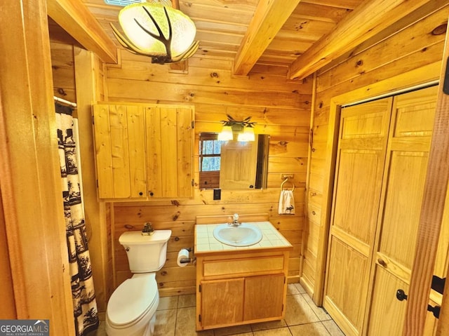 bathroom with a closet, toilet, wood walls, tile patterned flooring, and beamed ceiling