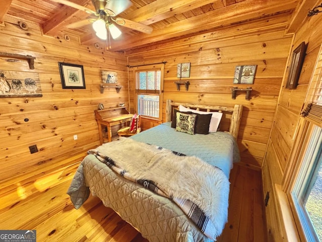 bedroom featuring beamed ceiling, wood finished floors, wood ceiling, and wooden walls