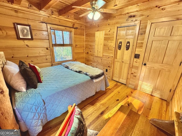 bedroom with light wood-type flooring, beam ceiling, wooden ceiling, and wood walls