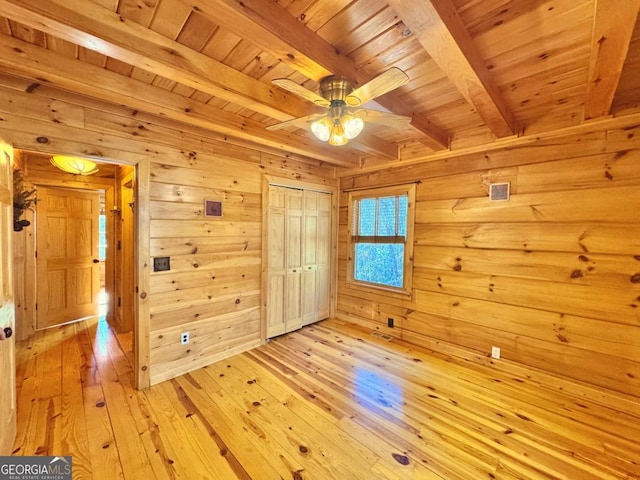 interior space featuring light wood-type flooring, wood walls, wood ceiling, and beamed ceiling