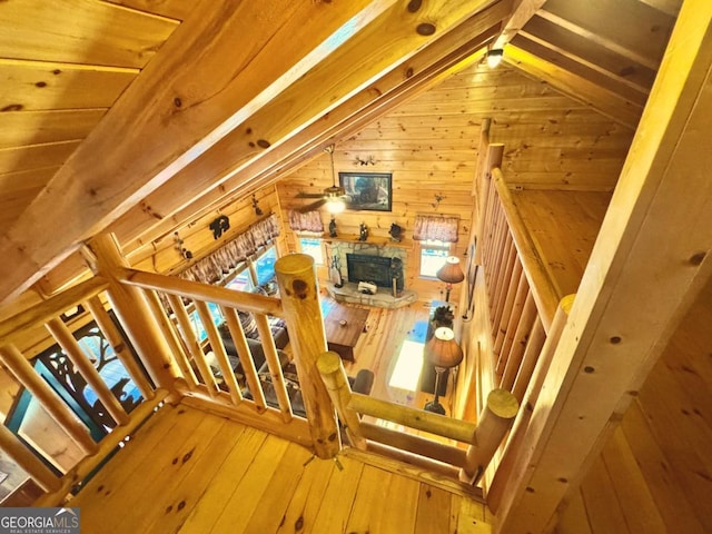 stairway featuring lofted ceiling, a healthy amount of sunlight, wood walls, and wood finished floors