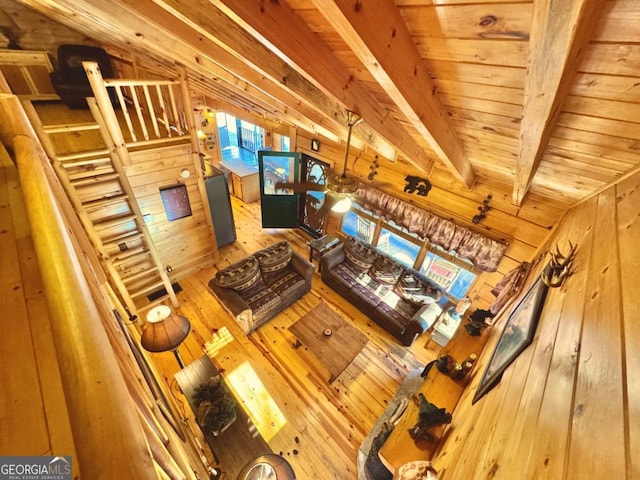 living area featuring wood ceiling, vaulted ceiling with beams, wooden walls, and wood finished floors