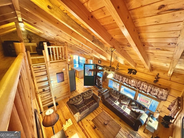 living area featuring wooden walls, wood ceiling, lofted ceiling with beams, and wood finished floors