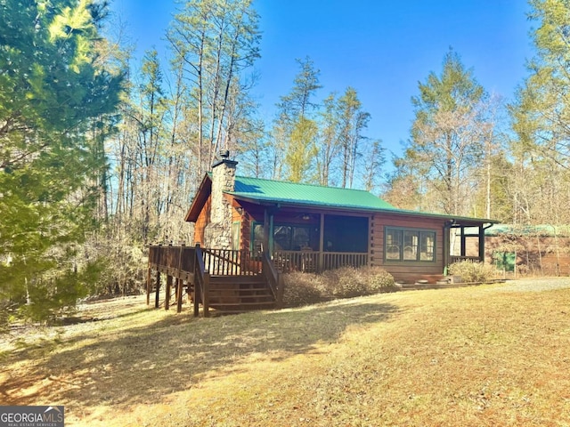 view of front of house with metal roof, a chimney, and a front lawn