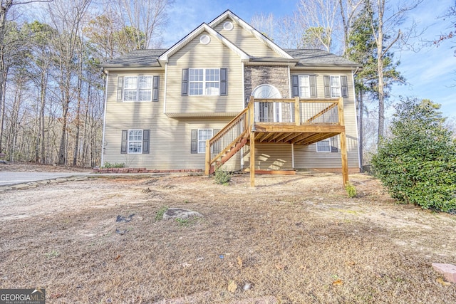 raised ranch with a deck, stone siding, and stairway