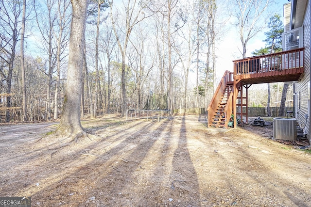 view of yard with stairs, a deck, and central AC