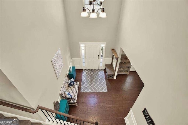 entryway with stairway, dark wood-style flooring, a high ceiling, a decorative wall, and a notable chandelier