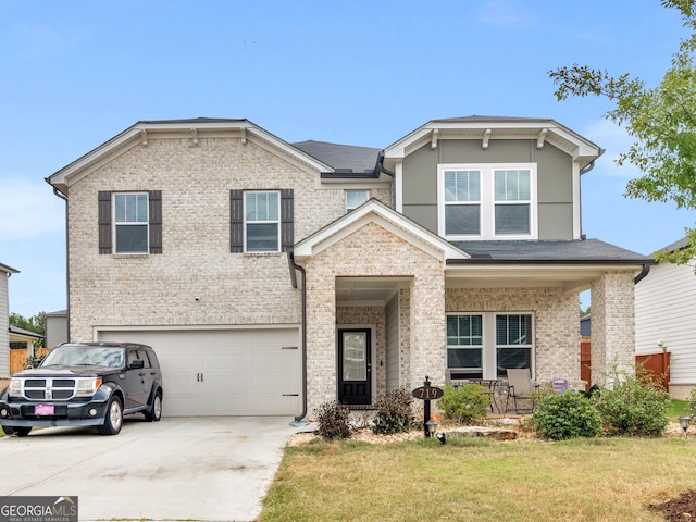 view of front of house featuring brick siding, covered porch, a front yard, a garage, and driveway