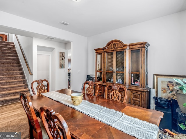 dining space featuring visible vents, stairway, and wood finished floors