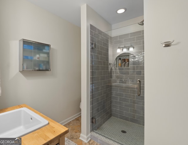 full bath featuring a sink, a shower stall, and baseboards