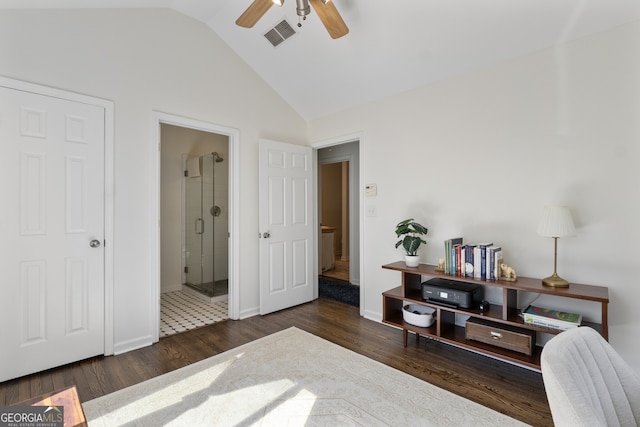 interior space featuring dark wood finished floors, lofted ceiling, visible vents, a ceiling fan, and ensuite bath