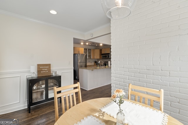 dining space with ornamental molding, dark wood finished floors, and a decorative wall