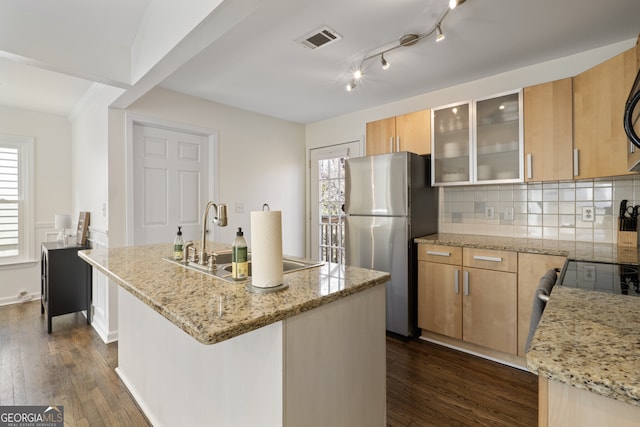 kitchen featuring a center island with sink, visible vents, glass insert cabinets, freestanding refrigerator, and a healthy amount of sunlight