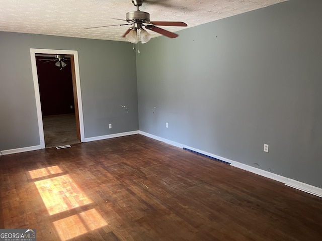 empty room with visible vents, baseboards, a ceiling fan, dark wood finished floors, and a textured ceiling