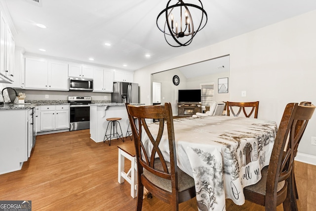 dining area featuring a chandelier, vaulted ceiling, wood finished floors, and recessed lighting