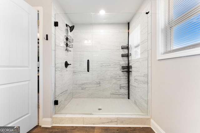 full bathroom with a shower stall and baseboards