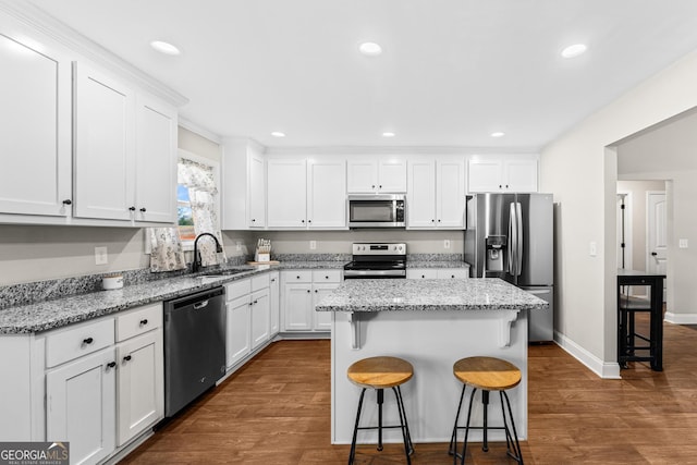 kitchen with appliances with stainless steel finishes, a center island, white cabinets, and a kitchen breakfast bar