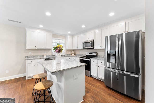 kitchen featuring stainless steel appliances, white cabinetry, visible vents, a center island, and dark wood-style floors