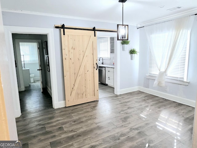 unfurnished dining area featuring a barn door, baseboards, visible vents, wood finished floors, and crown molding