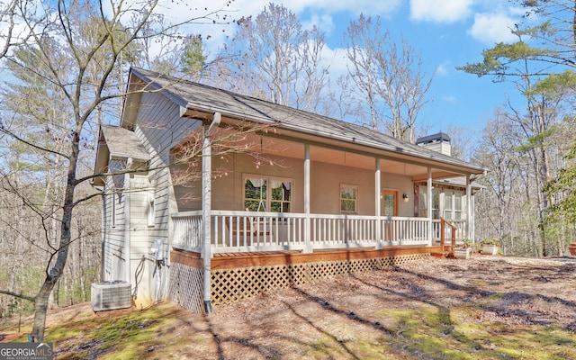 view of side of property featuring covered porch, a chimney, and central air condition unit