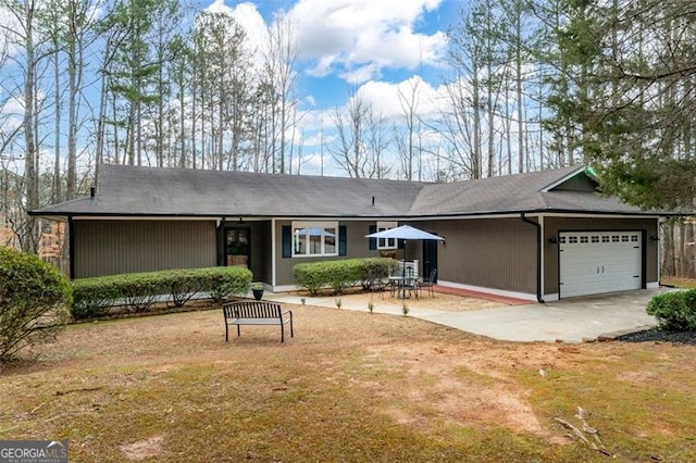 single story home with concrete driveway, a patio, an attached garage, and a front yard