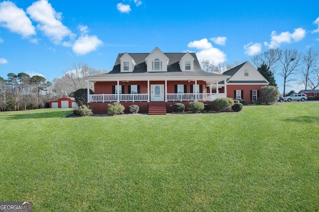 view of front of property featuring covered porch, a front yard, an outdoor structure, and a garage