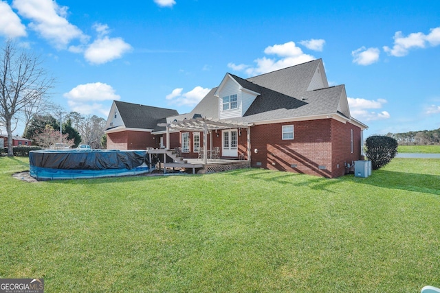 rear view of house with a yard, a covered pool, brick siding, and a pergola