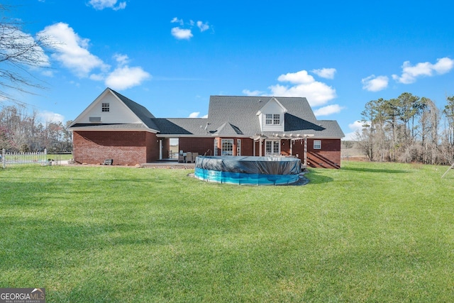 rear view of house featuring a covered pool, a lawn, a pergola, and brick siding