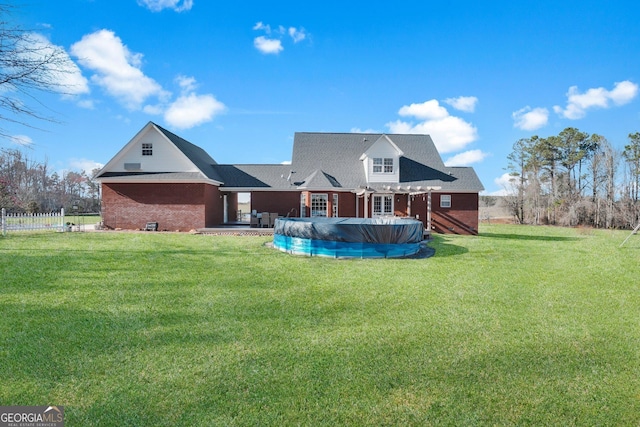 rear view of house with brick siding, a yard, fence, a pergola, and a covered pool