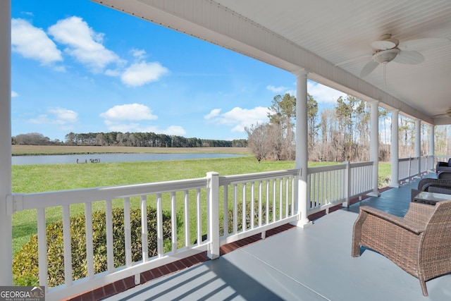 deck with ceiling fan, a porch, a lawn, and a water view