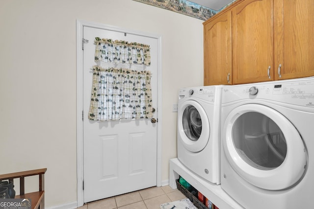 clothes washing area featuring light tile patterned flooring, washing machine and dryer, and cabinet space