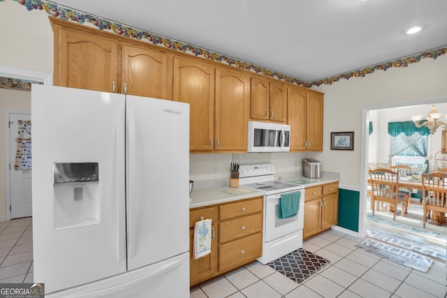 kitchen with light tile patterned floors, a notable chandelier, white appliances, light countertops, and brown cabinetry