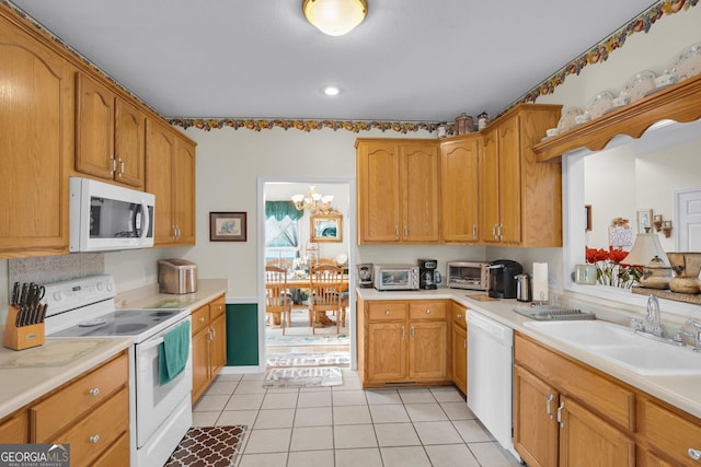 kitchen with brown cabinets, light countertops, light tile patterned flooring, a sink, and white appliances